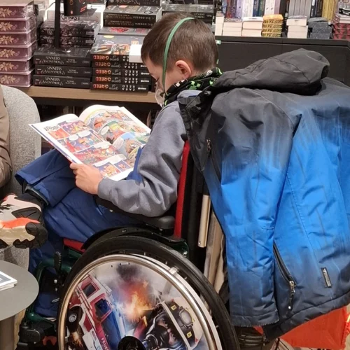 Finn aus Jena im Rollstuhl ein Comic lesend.