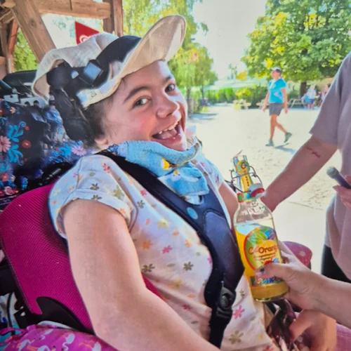 Emilia im Rollstuhl in die Kamera lachend